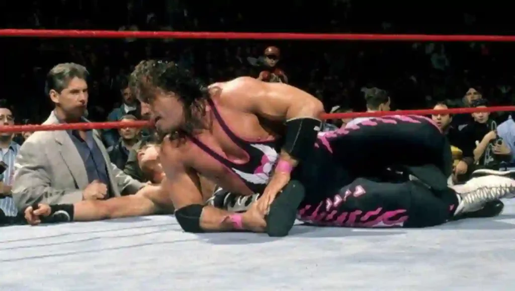 Bret Hart wrestles Shawn Michaels in the Montreal Screwjob match at Survivor Series 1997, with Vince McMahon watching from ringside.